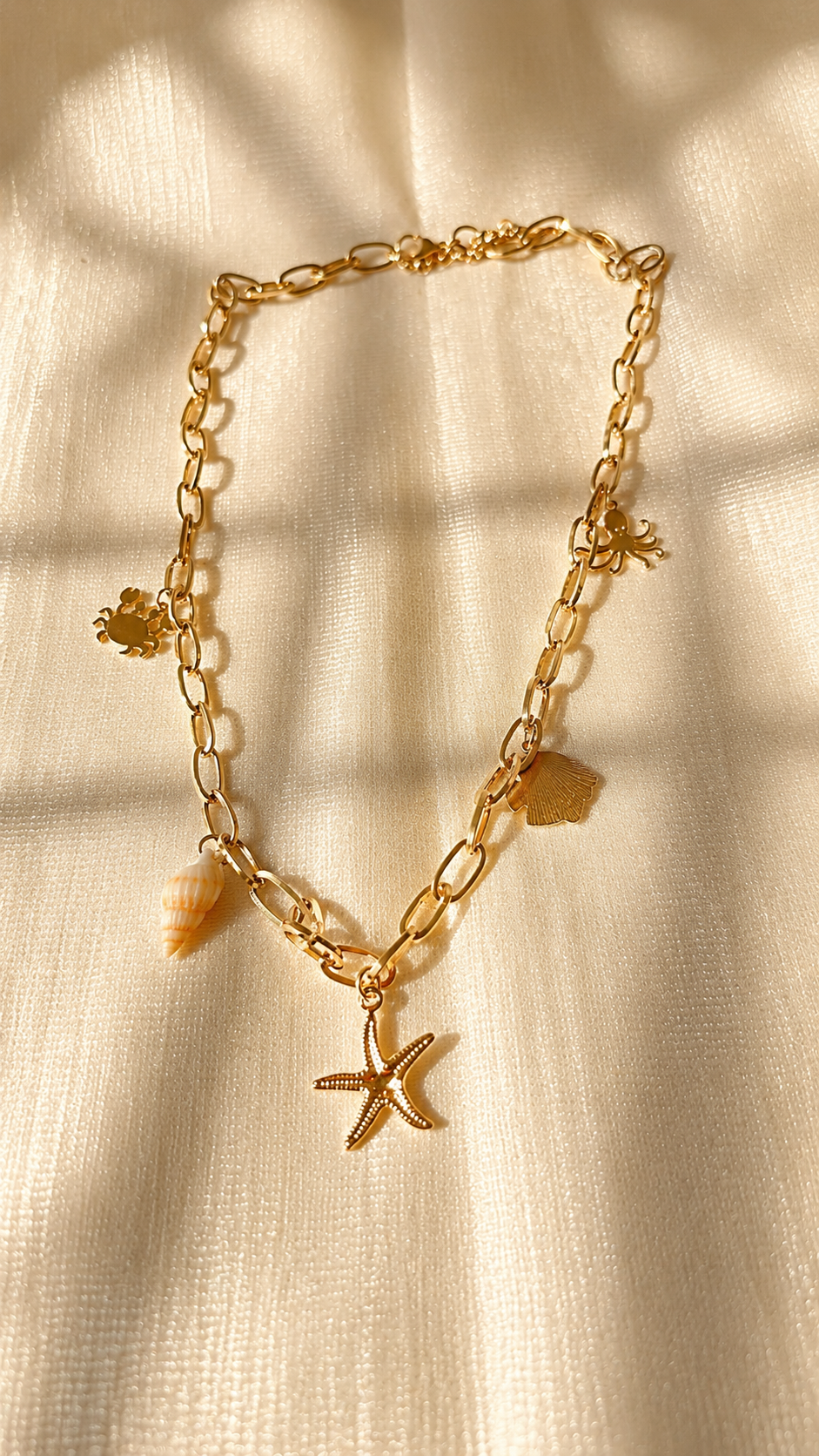 Gold ocean charm bracelet featuring starfish, shell, crab, and octopus charms with an anti-tarnish finish by Jewel Minimals.